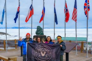 The 2022 field team at the "Chalet" in McMurdo Station where the flags of the 12 original signatory countries of the Antarctic Treaty are flown.