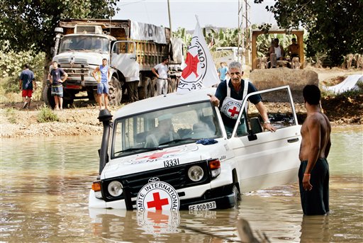 The driver of a vehicle of the International Committee of the Red Cross discusses how to extract his vehicle from the river with colleagues on the riverbank, after getting stuck whilst trying to drive across the Litani river north of Tyre in southern Lebanon Friday, Aug. 11, 2006. A truck carrying humanitarian food aid is seen behind. Aid workers are increasingly frustrated over the lack of access for delivering aid in Lebanon and Ronald Huguenin, spokesman for the International Committee of the Red Cross, said that Israel had refused to let a Greek ship carrying humanitarian aid and food to dock in either Tyre or Sidon. (AP Photo/Ben Curtis)